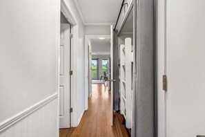 A hallway with white walls and wooden flooring leading to a room with a large window. - Top Floor Condo at Beach & Tennis Resort  Beachfront Pool & Golf access (Hilton Head Island)