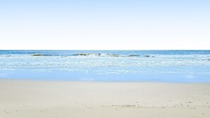 En strand med klare himmel og rolige bølger.