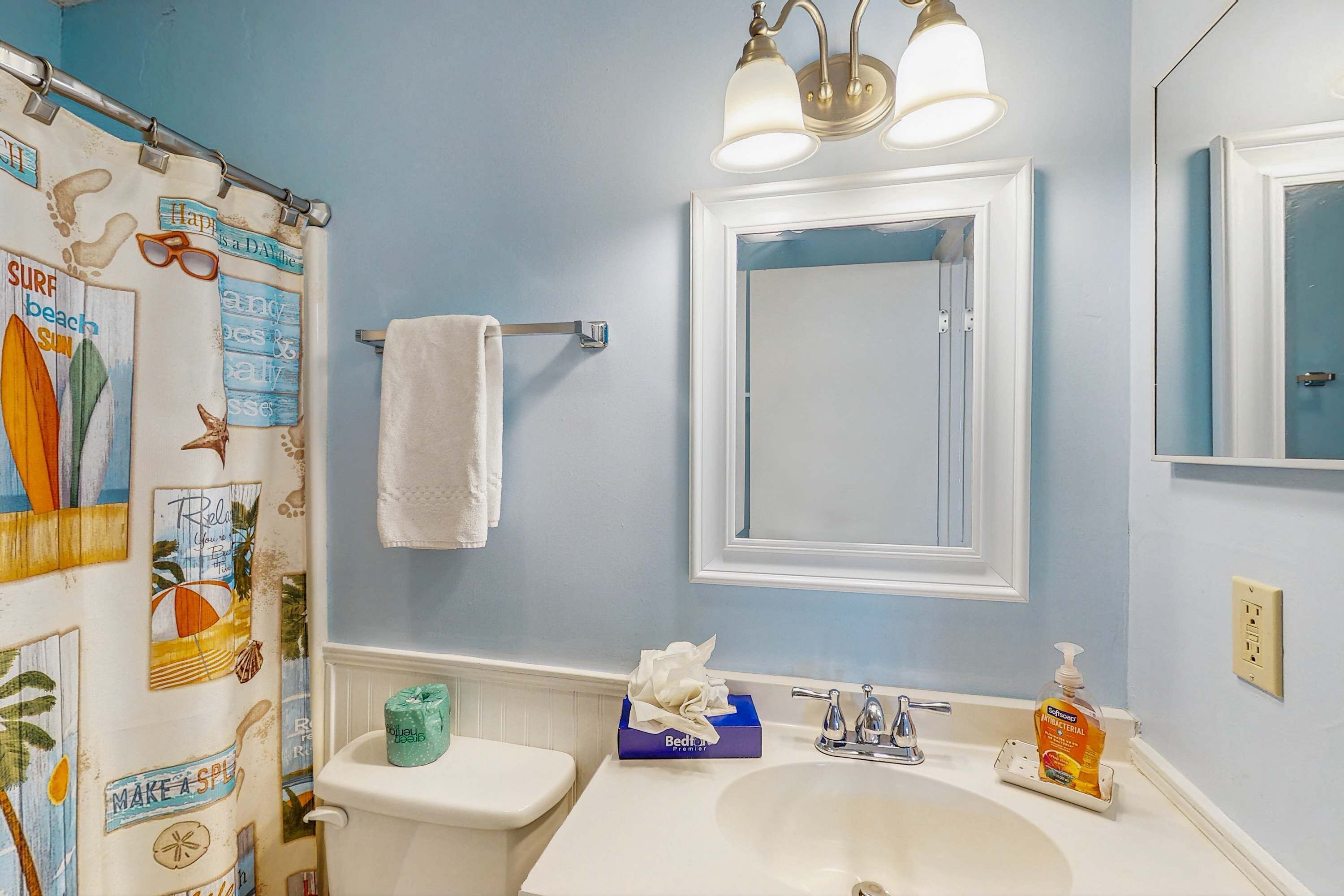 A bathroom with a toilet, sink, and mirror.