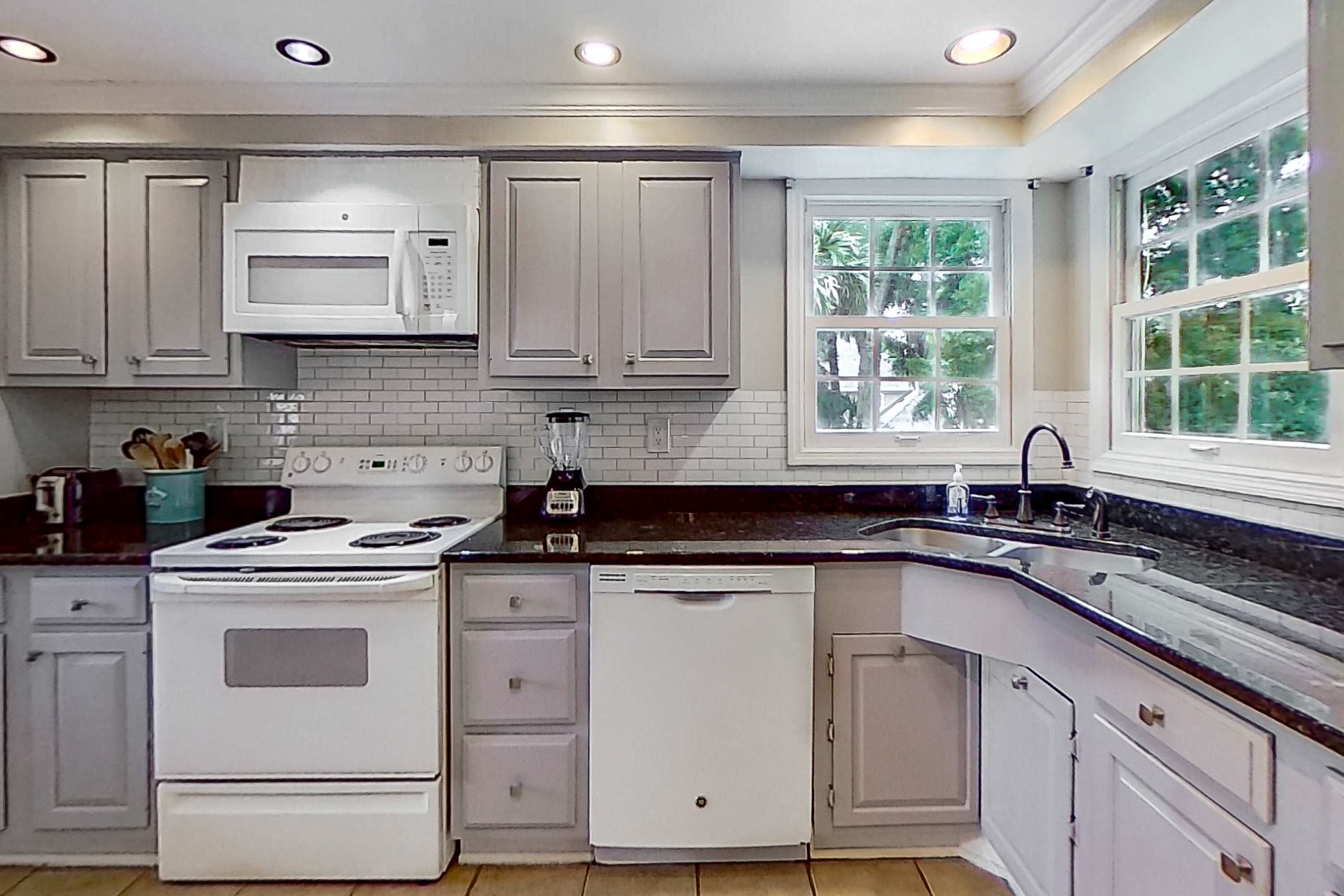 A kitchen with white cabinets, a stove, a microwave, and a dishwasher.