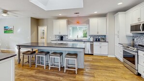 A modern kitchen with a central island, white cabinetry, stainless steel appliances, and a skylight. - Beautiful half acre estate home with private hot tub and passes to the shared pool (Hilton Head)
