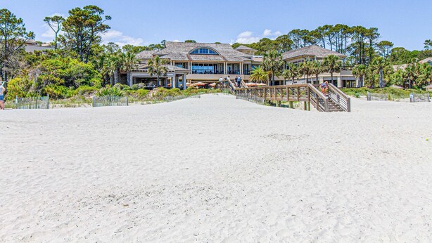 A beachfront property with a large house, a covered walkway, and a sandy beach. - Coastal charmer villa with cove front balcony & trolley  walk to beach (Hilton Head)