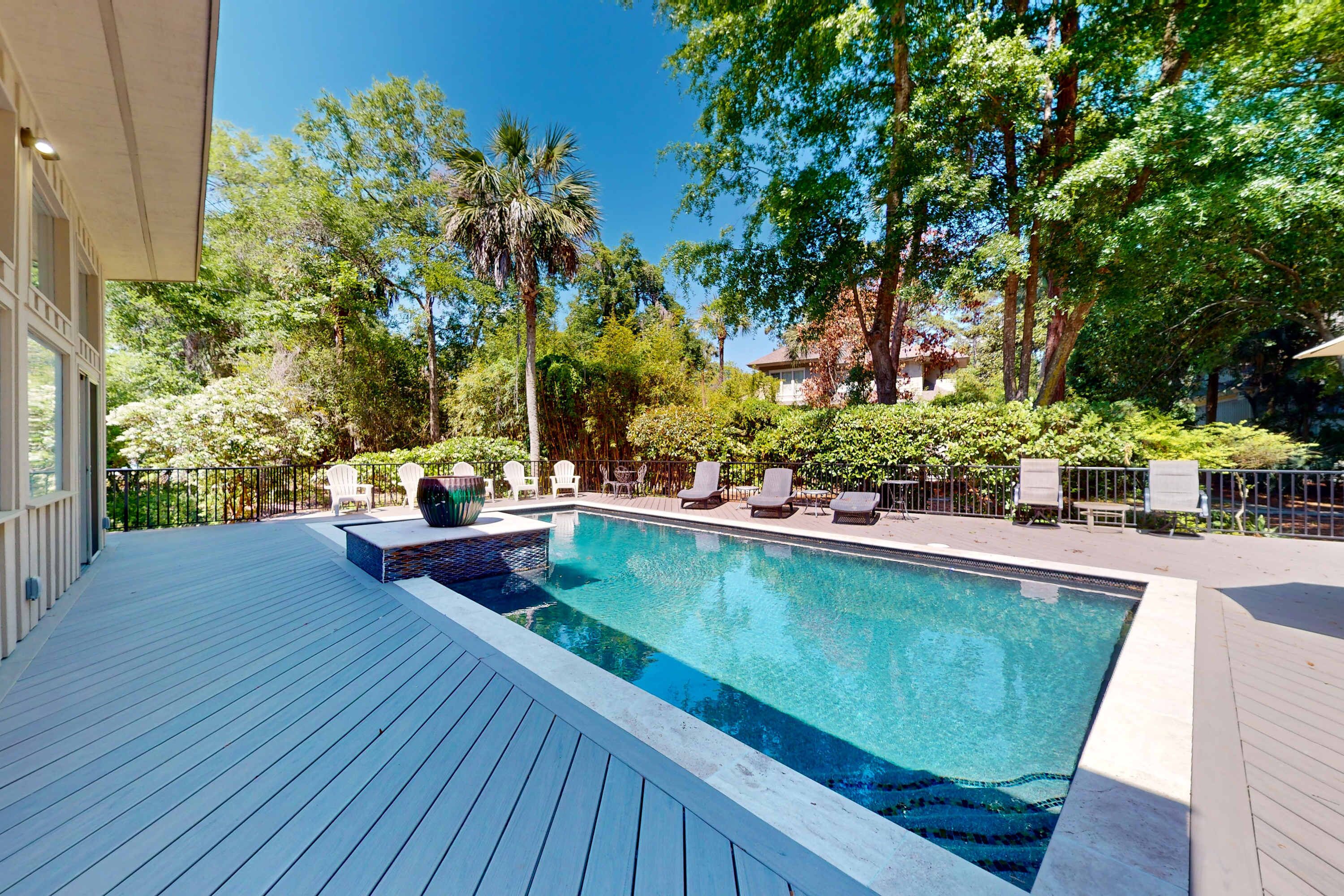 A swimming pool with lounge chairs and a deck.