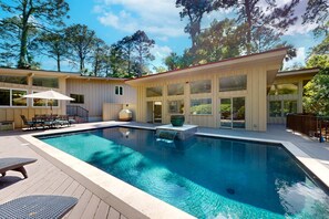 Una casa moderna con piscina, ventanas amplias y una terraza.