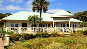 A two-story building with a covered porch and a white fence. - Relaxing Evian villa with patio, pool, tennis, pickleball, beach, golf, Dogs ok (Hilton Head)