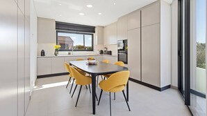 Eine moderne Küche mit Essbereich, großen Fenstern und Blick ins Freie.
