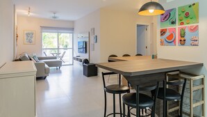 Ett modernt vardagsrum med en soffa, ett matbord med stolar, en tv och konstverk på väggarna.