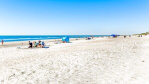 A beach with people, tents, and beach chairs. - Sunny condo with ocean view balcony & beach access (Hilton Head)