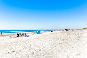 Ein Strand mit Menschen, Zelten und Liegestühlen.