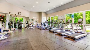 A gym with treadmills, weight machines, and a clock on the wall. - Sunny condo with ocean view balcony & beach access (Hilton Head)