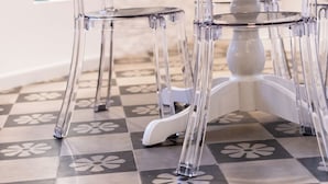 Un comedor con una mesa y sillas, piso con diseño y obras de arte en las paredes.
