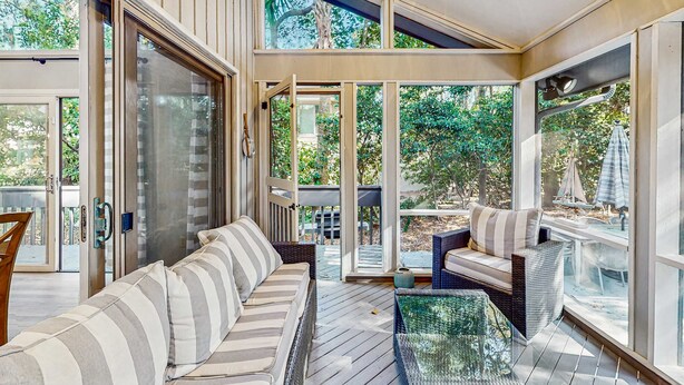 A modern outdoor living area with a sofa, a glass table, and a view of the garden. - Fully Renovated Sea Pines Home w Private Pool Six Rows from the Water  Dogs OK (Hilton Head)
