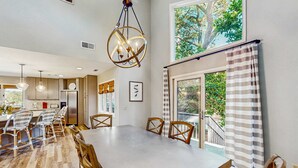 A spacious dining area with a large table and chairs, a chandelier, and a view of greenery outside. - Fully Renovated Sea Pines Home w Private Pool Six Rows from the Water  Dogs OK (Hilton Head)