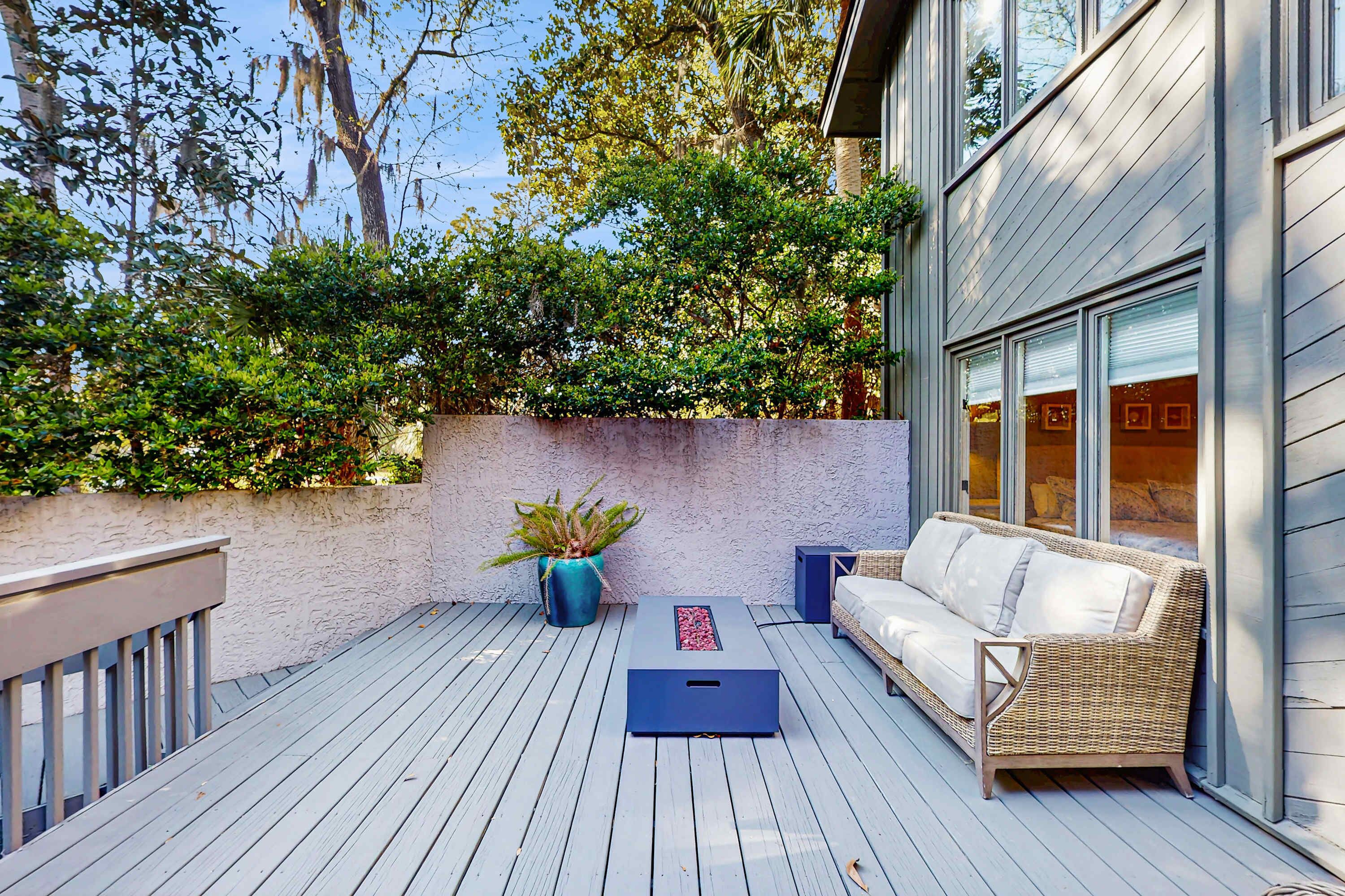 A deck with a wicker sofa, a blue planter, and a small table.