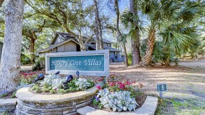 A sign for Hickory Cove Villas with a stone planter and flowers in front. - Sunny getaway with full kitchen, furnished deck, and shared pool (Hilton Head)