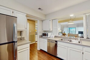 A modern kitchen with white cabinetry, stainless steel appliances, and a built-in dishwasher. - Condo with soaring ceilings, a deck, lagoon views, & shared tennis (Hilton Head)