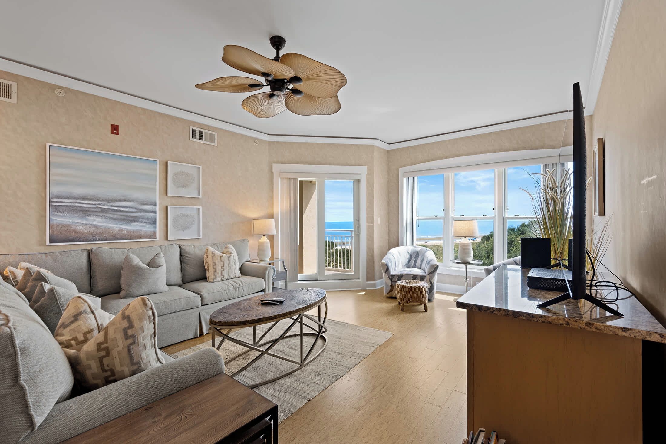 A spacious living room with a sofa, coffee table, and a television on a stand.
