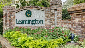 A brick wall with the name 'Leamington' and a logo, surrounded by green shrubs and flowers. - Bright & Airy Retreat with Balcony Views, Walkable Beach Access & Central Location (Hilton Head)