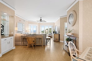 A spacious kitchen with a central island, large windows, and a ceiling fan. - Bright & Airy Retreat with Balcony Views, Walkable Beach Access & Central Location (Hilton Head)