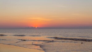 A beach with waves at sunset. - Bright & Airy Retreat with Balcony Views, Walkable Beach Access & Central Location (Hilton Head)