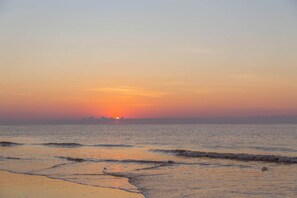 Ein Strand mit Wellen bei Sonnenuntergang.