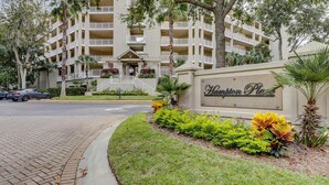 A multi-story hotel with a landscaped entrance, a sign reading 'Hampton Plaza,' and a paved driveway. - Bright & Airy Retreat with Balcony Views, Walkable Beach Access & Central Location (Hilton Head)