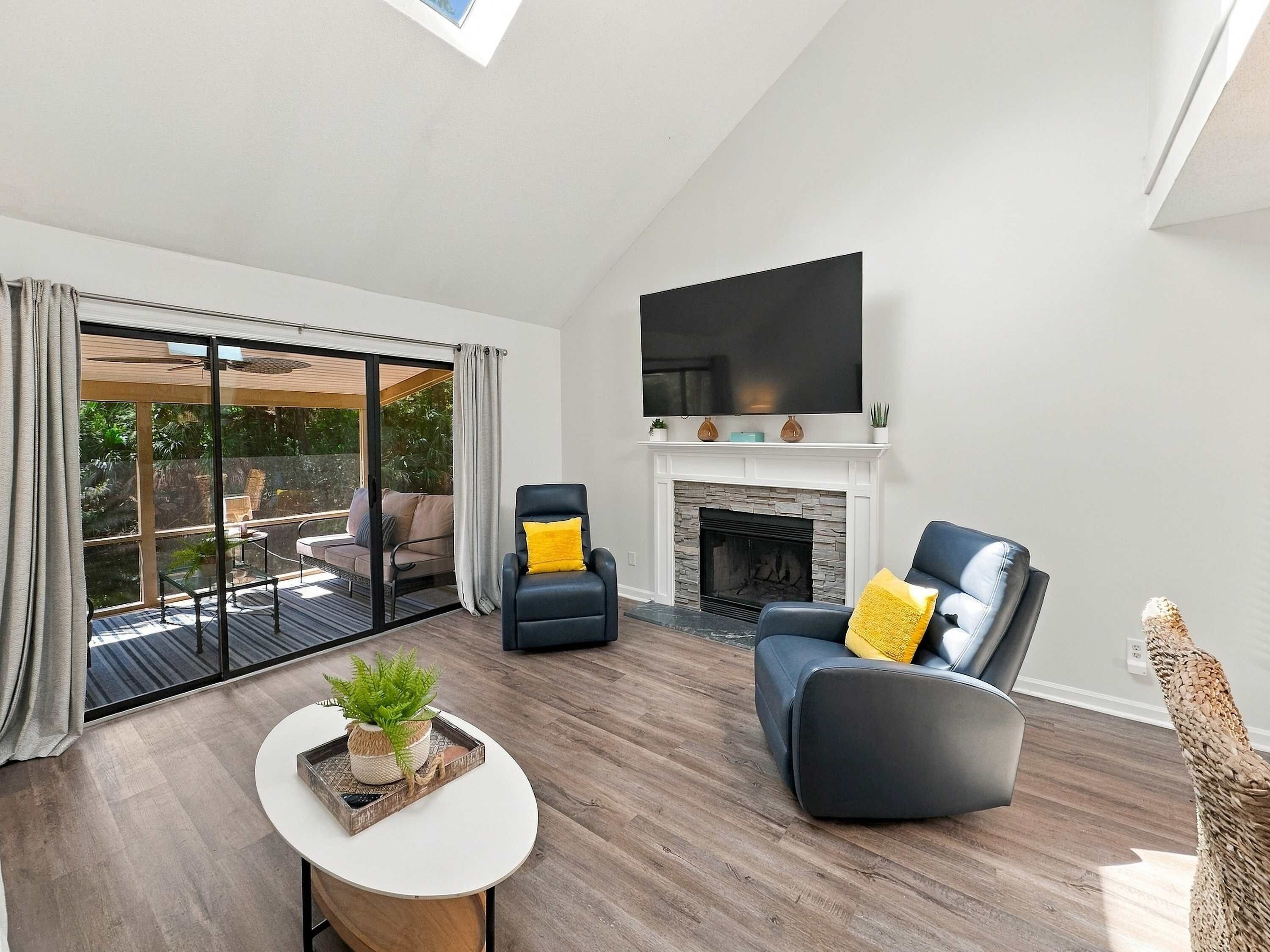 A modern living room with a fireplace, a flat-screen TV, and a large sliding glass door leading to a patio.