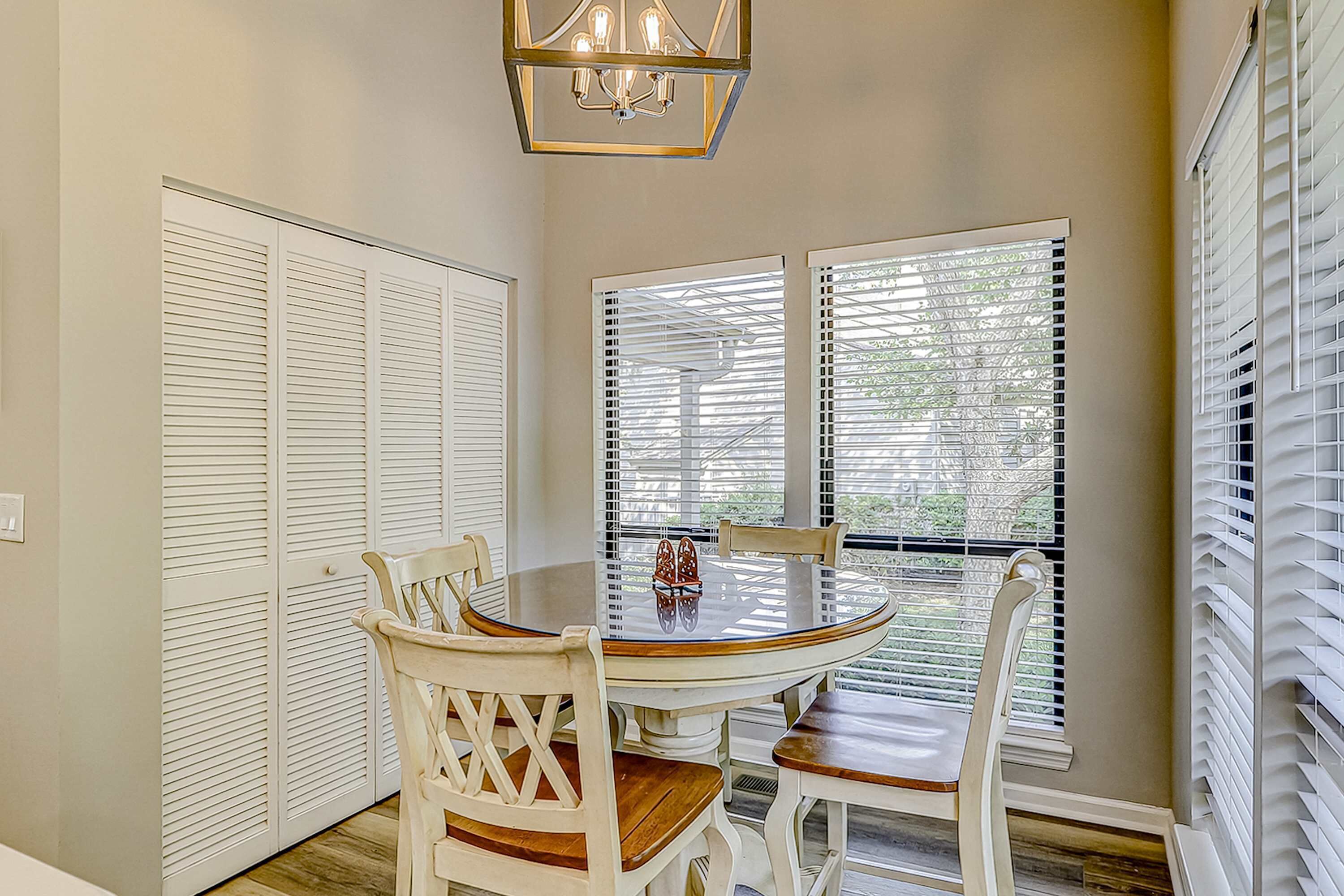 A dining area with a round table, white chairs, and a chandelier.