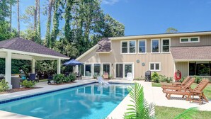 Une propriété résidentielle dotée d’une piscine, d’un espace extérieur aménagé et d’un patio couvert.