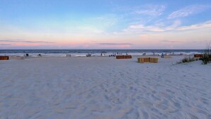 Une vaste plage de sable bordée d’une clôture en bois, sous un ciel dégagé.
