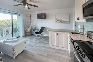 A modern kitchen with a large stove, white cabinets, and a balcony with a hammock. - Updated condo in beachfront complex with pools & hot tubs - walk to dining (Hilton Head)