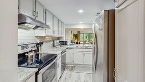 Una cocina moderna con gabinetes blancos, electrodomésticos de acero inoxidable y vistas al exterior.