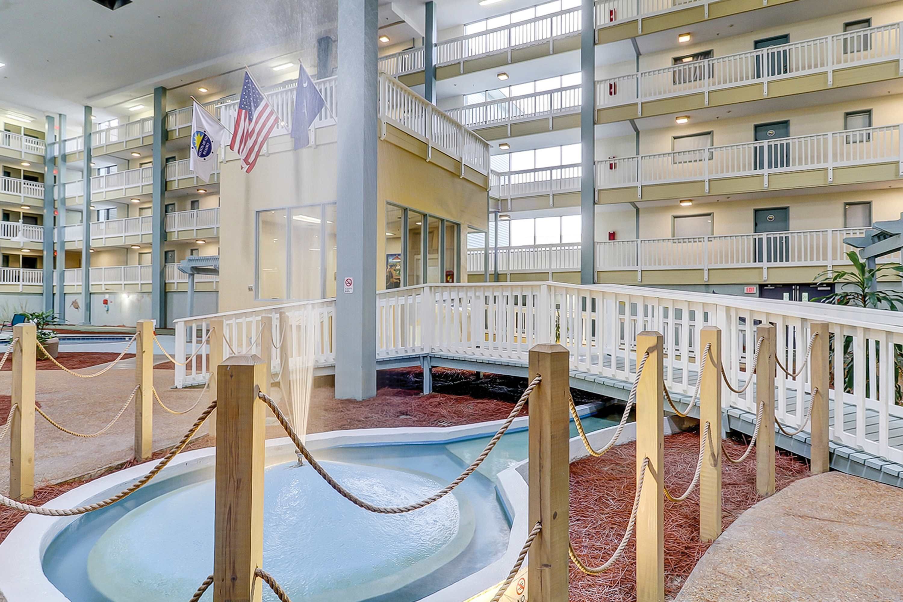 Ein mehrgeschossiges Innenhof-Atrium mit Schwimmbad, Holzwertungen und Flaggen.