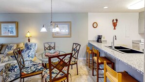 Uma sala de jantar com uma mesa redonda, cadeiras e um lustre.