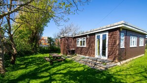 Une petite cabane en bois dotée d’une terrasse, entourée d’une végétation luxuriante.