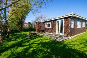 Une petite cabane en bois dotée d’une terrasse, entourée d’une végétation luxuriante.