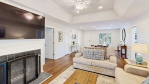 Un salón amplio con chimenea, ventilador de techo y televisor grande.