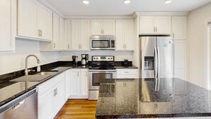 Una cocina moderna con armarios blancos, electrodomésticos de acero inoxidable y encimera de granito.