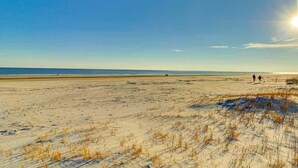 Una extensa playa de arena con dunas y cielo despejado.