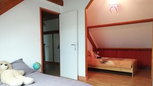 Un dormitori amb un llit, un os de peluix, un globus i un sostre inclinat.