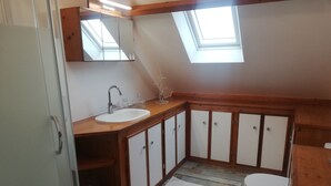 Un bany amb un lucernari, mobles de fusta, un lavabo i un vàter.