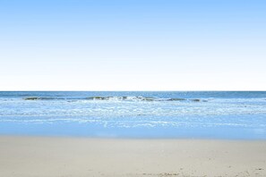 En strand med klar himmel och stilla hav.