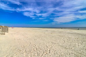 A sandy beach with a wooden fence on the left and a clear blue sky. - Beach-view condo in oceanfront complex with outdoor pool, beach access & balcony (Hilton Head)