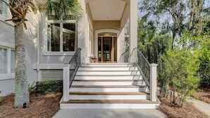 Ein Haus mit Veranda, Treppe und einer Palme.