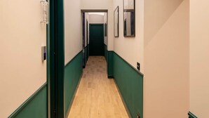 A hallway with a wooden floor, green trim, and a door at the end. - Emotional Shower & Absolute Silence (Rome)