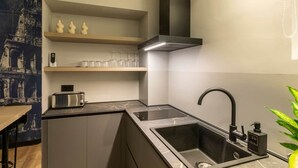 Una cocina compacta con tostadora integrada, un lavamanos con grifo moderno y una pequeña estantería con adornos.