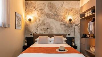 A hotel room with a bed, two wall sconces, a wardrobe, and a decorative wall.