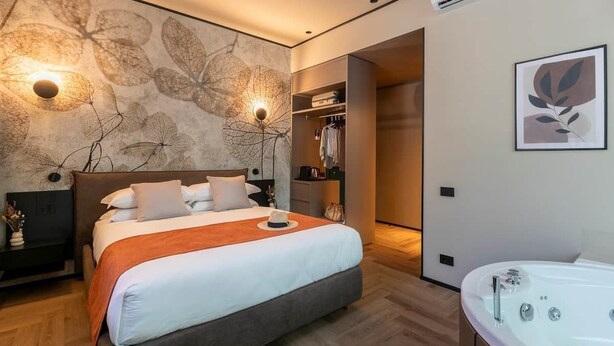 Ein modernes Schlafzimmer mit einem großen Bett, einem begehbaren Kleiderschrank, einem Badezimmer mit Badewanne und einer Wand mit einem Blattmuster.