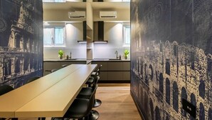 A modern kitchen with a long table and chairs, air conditioning units, and a view of the cityscape through large windows. - Relax Hot Tub – San Giovanni (Rome)