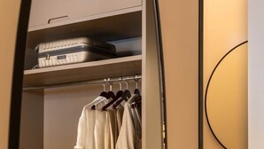 A walk-in closet with hanging clothes, a suitcase, a coffee maker, and a handbag. - Relax Hot Tub – San Giovanni (Rome)
